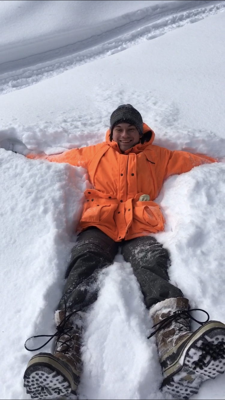 Photo of Eric Wuesthoff smiling in a jacket while laying in snow.