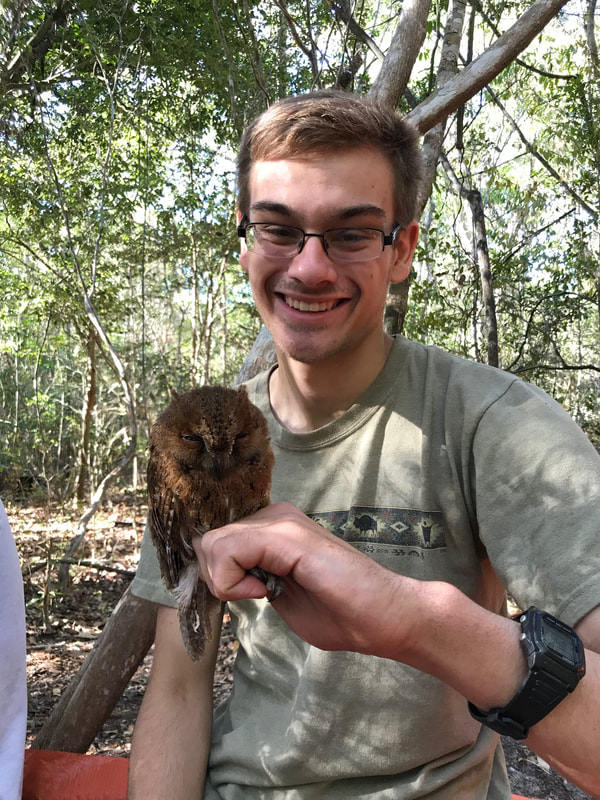 Photo of Eric Wuesthoff in a forest smiling and holding a small owl.